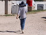 Shamima Begum is pictured wearing jeans, shirt and a blue hat as she walks through refugee camp